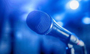 Close-up of a microphone on a stand under blue stage lighting.